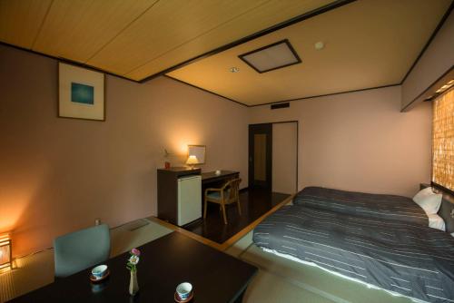 a bedroom with a bed and a desk and a table at Takamiya Hotel Lucent in Zao Onsen