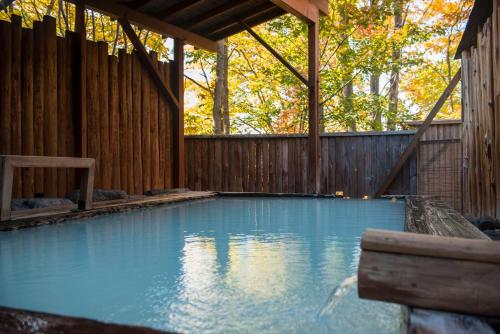 a swimming pool in a backyard with a wooden fence at Takamiya Hotel Lucent in Zao Onsen