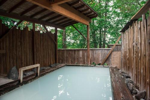 a swimming pool in a backyard with a wooden fence at Takamiya Hotel Lucent in Zao Onsen