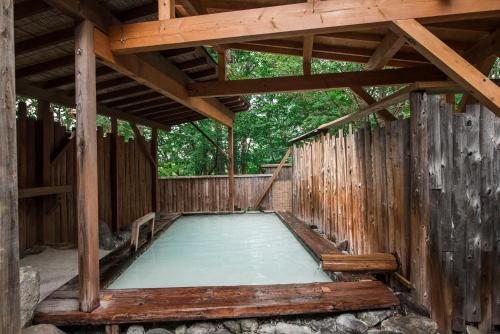 a pool of water in a wooden pool house at Takamiya Hotel Lucent in Zao Onsen