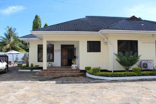 a white house with a black roof at IDC Guest House in Bagamoyo