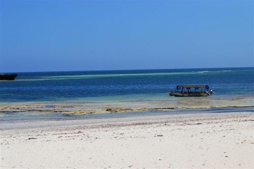 a boat sitting in the water on a beach at Turtle Bay Beach Club- All Inclusive in Watamu