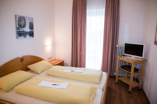 a hotel room with two beds and a television at Hotel Garni Trumm in Dillingen an der Donau