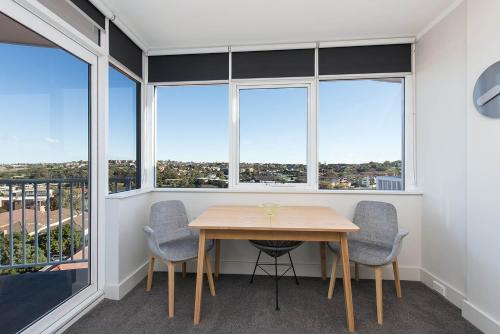 a table and chairs in a room with windows at Stunning Ocean View Apartment !!! in Sydney