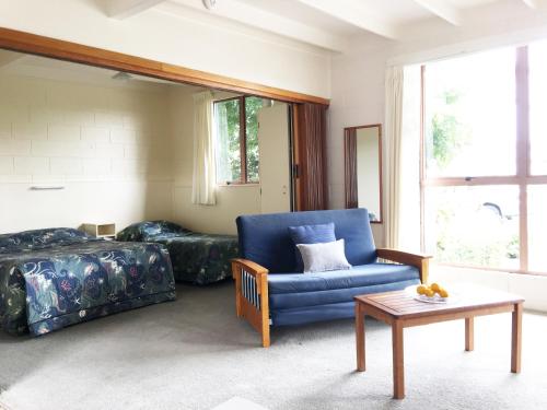a living room with a blue chair and a couch at Martinborough Motel in Martinborough 