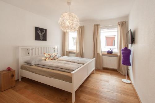 ein Schlafzimmer mit einem weißen Bett und einem Kronleuchter in der Unterkunft Wohnen an der Juliuspromenade Stadt in Würzburg