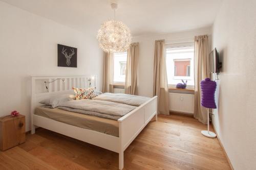 a bedroom with a white bed and a chandelier at Wohnen an der Juliuspromenade Stadt in Würzburg