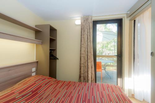 une chambre avec un lit et une porte coulissante en verre dans l'établissement VTF Les Oyats Sylvadoures, à Maubuisson