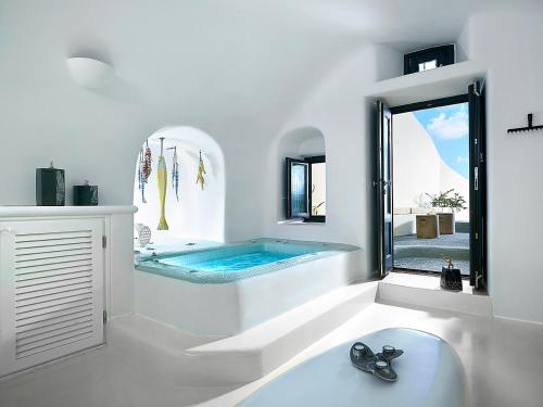 baño blanco con bañera y piscina en Blue Canaves Boutique Villa, en Oia