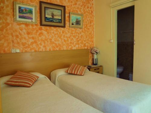 a bedroom with two beds and two paintings on the wall at Pensión Dani in Barcelona