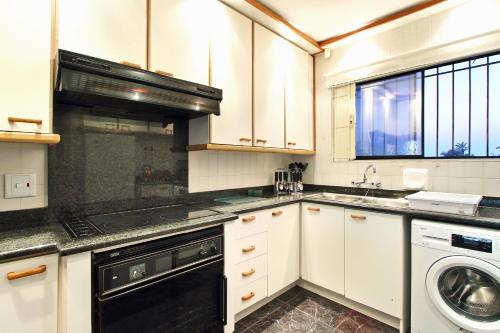 a kitchen with white cabinets and a black appliance at Cap Du Mont Cape Town in Bloubergstrand