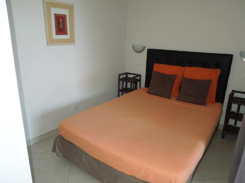 een slaapkamer met een groot bed met oranje kussens bij Appartement vue sur mer in Santa-Maria-di-Lota