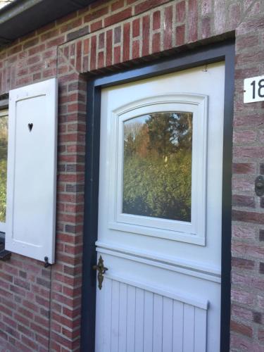 a white door on a brick building with a window at De Heijense Molen Retro Camping in Heijen