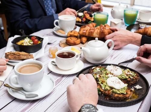 a table topped with plates of food and cups of coffee at Cottons Hotel and Spa in Knutsford