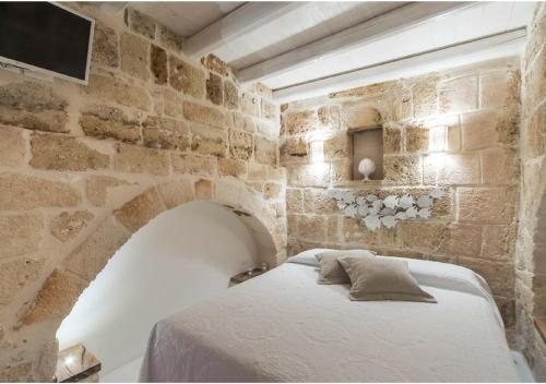 ein Schlafzimmer mit einem Bett in einer Steinmauer in der Unterkunft La dimora dei nonni in Monopoli