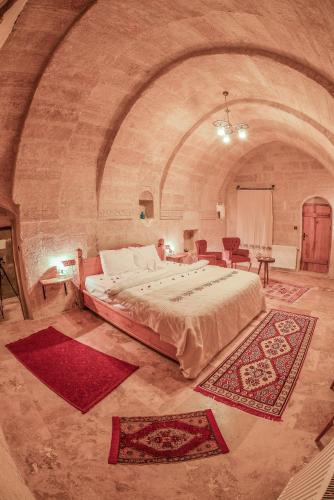 a bedroom with a large bed in a stone room at Mosaic Cave Hotel in Göreme