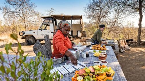 a woman sitting at a picnic table with food at Nyati Safari Lodge in Hoedspruit