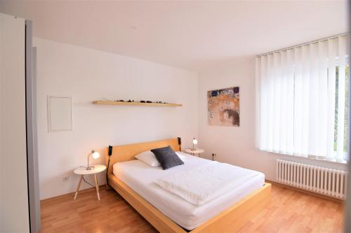 a white bedroom with a bed and a window at Apartment D&D Spessart in Ettlingen