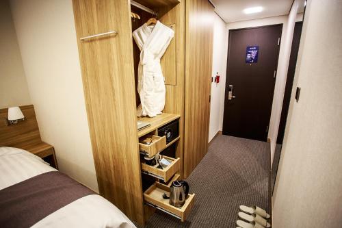 a hotel room with a suit hanging on a closet at Utop Ubless Hotel Jeju in Jeju