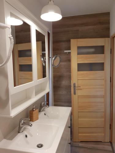 een badkamer met een wastafel, een spiegel en een deur bij Zakątek Mazurski GIM in Teerau