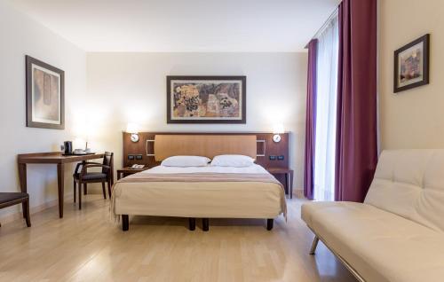 una camera con letto, tavolo e divano di Stadio Hotel a Piacenza