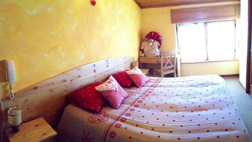 a bedroom with a bed with red and white pillows at Hotel al Sole in Auronzo di Cadore