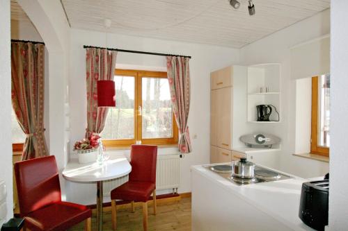 a kitchen with a white table and red chairs at Altensberger Hof in Gestratz