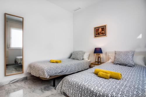 a bedroom with two beds and a mirror at Encantador Ático con Terraza in Seville