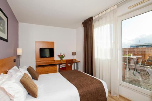 een hotelkamer met een bed en een groot raam bij Séjours & Affaires Rouen Normandie in Rouen