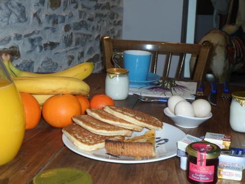 Ein Tisch mit einem Teller Toast, Orangen und Bananen. in der Unterkunft Les Colombes de la Baie du Mont Saint-Michel in Aucey-la-Plaine