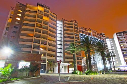 two tall buildings and palm trees in a city at night at Knightsbridge 407 by HostAgents in Cape Town