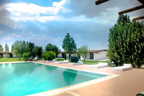 una piscina in un cortile alberato di Masseria Protomastro Hotel a Gravina in Puglia