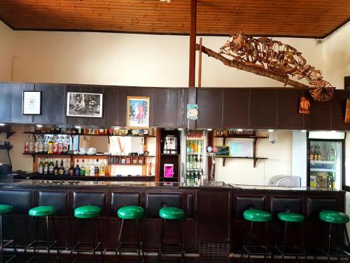 a bar with green stools in a restaurant at Hotel le Trianon in Antsirabe