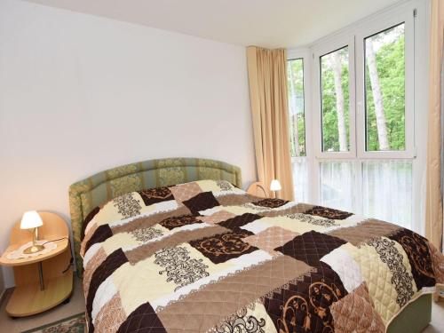 1 dormitorio con edredón en una cama con ventana en Ferienwohnung-8-3 en Baabe