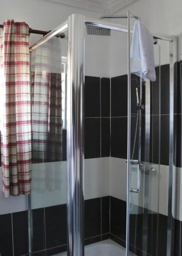 a bathroom with a shower with black and white tiles at Eden Vale Hotel in Ajiringano