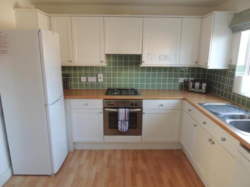 a kitchen with white cabinets and a stove and a refrigerator at Mountfield in Freshwater