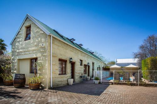 an old stone house with a brick courtyard at 88 Baron van Reede Guesthouse in Oudtshoorn