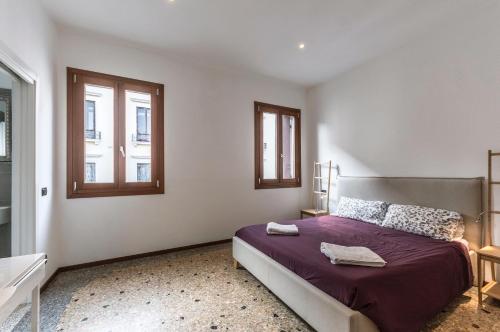 a bedroom with a bed and two windows at Ca' d'Oro suite in Venice