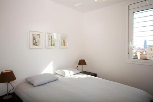 a white bedroom with a bed and a window at Sant Pau Terraces Apartments in Barcelona