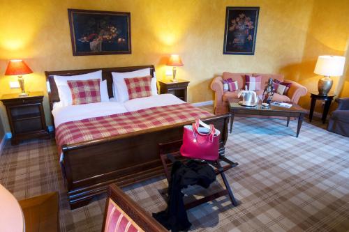 a bedroom with a bed and a couch and a table at Schlosshotel Hugenpoet in Essen