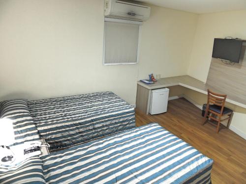 a hotel room with two beds and a desk at Hotel Hetropolis in São Bernardo do Campo