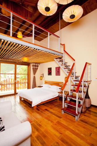 a bedroom with a bed and a spiral staircase at Yangshuo Coco Garden Hotel in Yangshuo