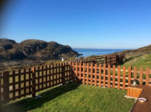 a wooden fence with the ocean in the background at Achmelvich View self catering in Lochinver