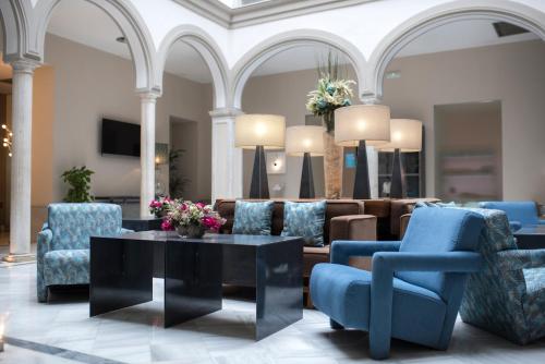 a living room with blue chairs and a table at Petit Palace Marques Santa Ana in Seville