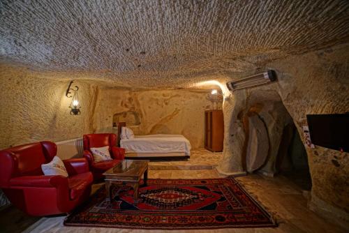 a room with a bed and a couch and a table at Jerveni Cave Hotel in Mustafapaşa