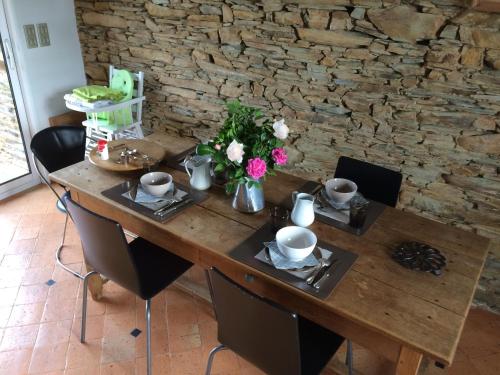 a wooden table with chairs and flowers on it at La Moulinière, jolie longère du XVIIè 25, chemin de la Source in La Jaille-Yvon