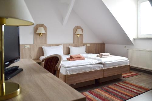 a bedroom with a bed and a desk in a room at Restaurant & Pension Storchenklause in Storkow
