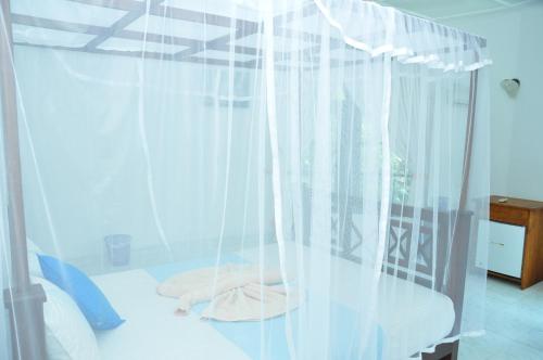 a bedroom with white curtains and a bed at Latheena Resort in Weligama