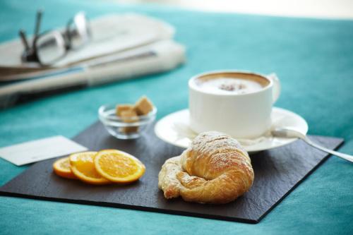 a tray with a cup of coffee and a croissant and orange slices at Hotel Costa Azul in Palma de Mallorca