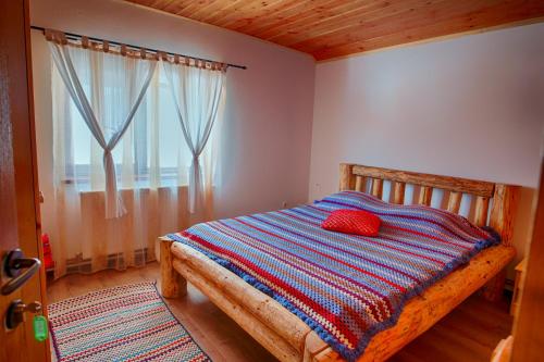 a bedroom with a wooden bed with a red pillow on it at Casa din Piatra in Poiana